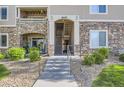 Close up of the exterior building entrance featuring stone accents, well-maintained landscaping and access to the units at 8445 S Holland Way # 205, Littleton, CO 80128