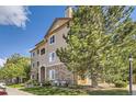Charming multi-story condo building with stone accents, green grass, mature tree, and a blue sky at 8445 S Holland Way # 205, Littleton, CO 80128