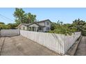 Street view of the home's exterior showing a white picket fence and a paved driveway at 947 S Yates St, Denver, CO 80219