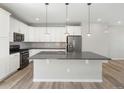 Bright kitchen with stainless steel appliances, gray countertops, island with pendant lighting, and white cabinetry at 3654 Penang Dr, Castle Rock, CO 80109