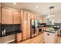 Kitchen featuring wood cabinets, stainless steel appliances, black countertops, and sleek backsplash at 453 S Quay Street, Lakewood, CO 80226