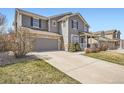 Attractive home featuring gray siding, stone accents, attached garage, and concrete driveway at 12185 S Grass River Trl, Parker, CO 80134