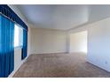 Empty living room featuring neutral carpet, white walls, and a large window providing natural light at 9202 W Virginia Pl, Lakewood, CO 80226