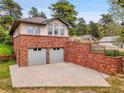 Home with two car garage featuring brick facade and retaining wall. Beautiful mountain views at 6094 Pyrenees Trl, Golden, CO 80403