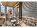 Inviting front porch with stone pillars and wrought iron seating, perfect for relaxing outdoors at 17851 E 103Rd Ave, Commerce City, CO 80022