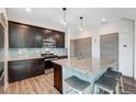 Modern kitchen with dark cabinetry, granite countertops, and a stylish center island with seating at 17851 E 103Rd Ave, Commerce City, CO 80022