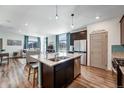 Open-concept kitchen with stainless steel appliances and island seating, flowing into the living area at 17851 E 103Rd Ave, Commerce City, CO 80022