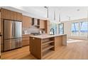 Bright, modern kitchen with wood cabinets, stainless steel appliances, and large island with shelves for storage at 2323 S High St, Denver, CO 80210