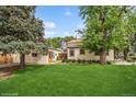 Spacious backyard with lush green lawn, mature trees, and detached garage at 113 S 4Th Ave, Brighton, CO 80601