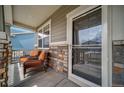 Inviting covered front porch featuring a seating area with wicker chairs and stone column accents at 18103 House Finch Ln, Parker, CO 80134