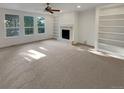 Spacious living room with a cozy fireplace, built-in shelving, large windows, and neutral carpeting at 24955 E Roxbury Pl, Aurora, CO 80016