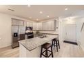 Modern kitchen with gray cabinets, granite countertops, and stainless steel appliances, plus an island with bar stool seating at 14700 E 104Th Ave # 1404, Commerce City, CO 80022