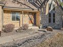 Brick front entrance with a wooden door and landscaping at 6141 W Evans Pl, Lakewood, CO 80227