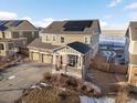 Aerial view of a two-story home featuring a three-car garage, covered porch, and solar panels on the roof at 3140 S Nepal Way, Aurora, CO 80013