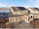 A high aerial view showcasing a two-story house with a three-car garage, solar panels, and an inviting porch at 3140 S Nepal Way, Aurora, CO 80013