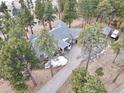 An aerial view of a home with a long driveway, surrounded by mature trees and a natural landscape, as well as an RV at 24860 N Mountain Park Dr, Evergreen, CO 80439