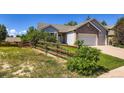 Inviting single-Gathering home featuring a three-car garage, a wooden fence and mature landscaping at 3859 Rawhide Cir, Castle Rock, CO 80104
