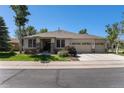 Charming single-story home with a three-car garage, stone accents, and lush green lawn at 11422 W Cooper Ave, Littleton, CO 80127