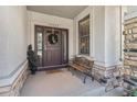 Inviting front porch featuring a cozy bench, stylish wreath, and beautiful stone detailing at 11422 W Cooper Ave, Littleton, CO 80127