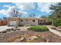 Inviting brick home with a well-kept lawn, complemented by mature trees and a sunny sky at 5540 E Jewell Ave, Denver, CO 80222