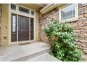 Inviting front entrance featuring a stone facade, covered porch, and a stylish multi-paneled front door at 297 N Coolidge Way, Aurora, CO 80018