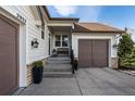 Inviting front entrance with a cozy bench, stylish sconces, and convenient attached two-car garage at 2932 Newbury Ct, Highlands Ranch, CO 80126