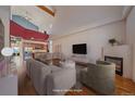 Open living room with vaulted ceiling, hardwood floors, fireplace, and view into the kitchen offering modern comfort at 190 Roslyn St # 802, Denver, CO 80230