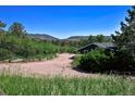 Exterior view of a green home nestled among trees with mountains visible in the distance at 4380 Sandstone Dr, Monument, CO 80132
