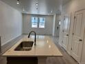 Open kitchen and living area featuring an island with a stainless steel sink and light wood floors at 17115 W 91St Ln, Arvada, CO 80007