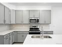 Modern kitchen with gray cabinets, stainless steel appliances, and quartz countertops at 17115 W 91St Ln, Arvada, CO 80007