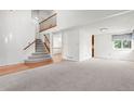 Bright living room featuring high ceilings, plush carpeting and a staircase to the upper level at 10890 Depew Pl, Broomfield, CO 80020
