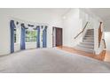 Spacious living room features large windows with blue curtains, a staircase, and hardwood accents at 10890 Depew Pl, Broomfield, CO 80020