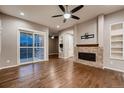 Hardwood-floored living room featuring a brick fireplace and large sliding glass doors, allowing for ample natural light at 3703 New Haven Cir, Castle Rock, CO 80109