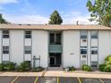 The exterior view of a two-story condominium with a light-colored facade, green trim, and multiple windows at 2150 S Vaughn Way # 302D, Aurora, CO 80014