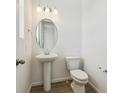 A pristine powder room with a pedestal sink, oval mirror and a white toilet at 24709 E 39Th Ave, Aurora, CO 80019