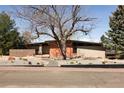A modern, single-story home with a low-pitched roof and horizontal windows, complemented by a stone walkway at 8 Lindenwood Dr, Littleton, CO 80120