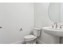 Clean bathroom with a pedestal sink, round mirror, and modern toilet at 8245 Cokedale Cir, Littleton, CO 80125