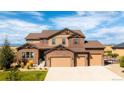 Stunning two-story home showcasing a stone and siding exterior with a spacious three-car garage at 953 Compass Dr, Erie, CO 80516