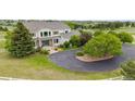Aerial view of a two story home with an asphalt driveway surrounded by mature landscaping and expansive lawn at 46093 Bristlecone Ct, Parker, CO 80138