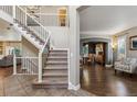 Elegant entryway with a staircase featuring iron railings and a view into the dining room with hardwood floors at 1300 W 13Th Ave, Broomfield, CO 80020