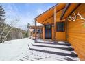 Inviting home entrance with wooden accents and snowy porch at 65 Cottonwood Dr, Evergreen, CO 80439