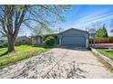 Charming single-story home featuring a blue exterior, arched doorway, and a two-car garage with a basketball hoop at 7065 Ingalls Ct, Arvada, CO 80003