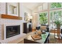 Cozy living room features a brick fireplace, vaulted ceilings, and large windows with natural light at 7264 Wembley Pl, Castle Pines, CO 80108