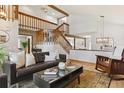 Open-concept living room with a wooden staircase, beamed ceiling, and hardwood flooring at 7264 Wembley Pl, Castle Pines, CO 80108