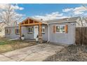 This gray home features a charming wooden porch, decorative shutters, and a paved driveway at 1970 Willow St, Denver, CO 80220