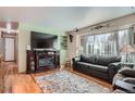 Inviting living room with fireplace, large TV, hardwood floors and ample natural light at 7005 S Ash Cir, Centennial, CO 80122