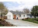 Quaint home with concrete driveway, orange door and a well-maintained lawn at 873 S Raritan St, Denver, CO 80223