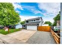 Charming two-story home with a well-manicured lawn, large driveway, and a gray and white facade at 7840 W Portland Ave, Littleton, CO 80128