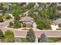 A high aerial view of a neighborhood with a two story home with a complex roof line nestled among lush trees at 9880 E Progress Cir, Greenwood Village, CO 80111