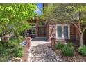 Charming brick home entrance with a beautiful wooden door, manicured landscaping, and a paved walkway at 9880 E Progress Cir, Greenwood Village, CO 80111
